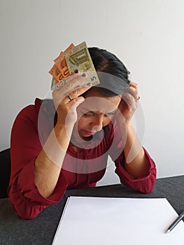 brunette woman with expression of despair and grabbing European money