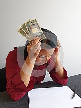 brunette woman with expression of despair and grabbing Japanese money