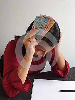 brunette woman with expression of despair and grabbing mexican money