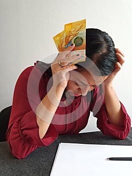 brunette woman with expression of despair and grabbing swiss money