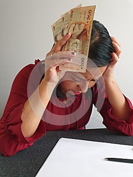 brunette woman with expression of despair and grabbing uruguayan money