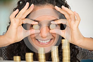 brunette woman facing camera stacking coins in piles on desk