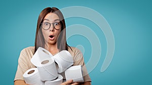 Brunette woman in glasses holds a lots of toilet paper, she opened her mouth in a surprise, copy space, isolated over