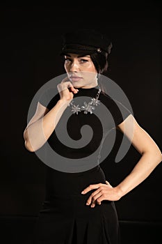 a brunette woman in a hat poses on a black background