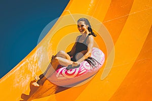 Brunette woman having fun on the water slide in aqua park