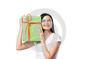 A brunette woman is holding a green gift box.