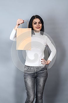 Brunette woman holding a paper shopping bag in her hand. Ecological packing