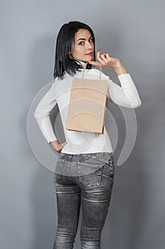 Brunette woman holding a paper shopping bag in her hand. Ecological packing