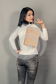 Brunette woman holding a paper shopping bag in her hand. Ecological packing