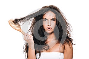 Brunette woman holding wavy unruly hair in comb isolated on white