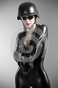 brunette woman in latex jumpsuit with heavy gun and helmet