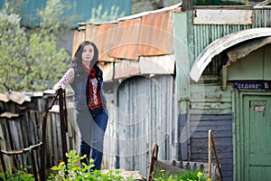 Brunette woman with long hair near old wooden fence in slum area