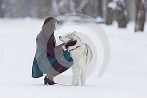 Brunette Woman Looking Eye To Eye with Her Lovely Husky Dog in Winter Forest