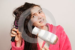 A brunette woman with matted hair dries it with a hair dryer. Hair care, overdried hair