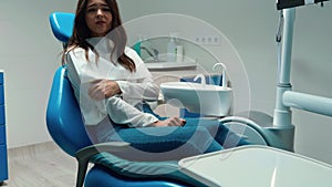 Brunette woman patient looks nervous while sitting in the dentist`s office feels frightened