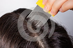 A brunette woman with pediculosis cleans her hair from lice and nits with a comb with small prongs. A lice comb