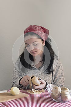 Brunette woman peeling potatoes