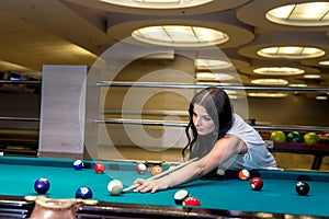 Brunette woman playing billiard, making a hit