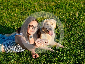 brunette woman playing with a dog white golden retriever on the grass in park.