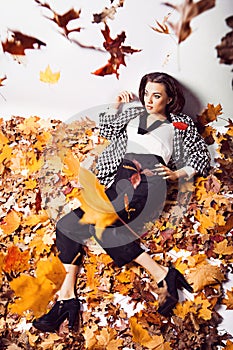 Brunette woman portrait in lying autumn leaves