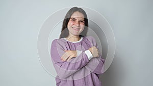 A brunette woman in purple warm pajamas hugs herself and enjoys the comfort of sleeping clothes