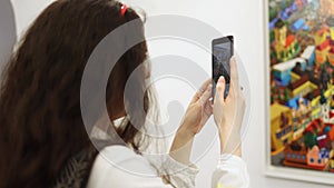 Brunette woman records video on her smartphone. Visit art exhibition