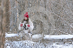 Brunette woman in red hat and mittens in winter forest with two mugs tea in anticipation of the beloved man