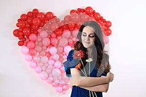 brunette woman with red heart balloons and flowers