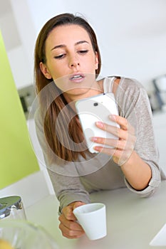 Brunette woman sending message with smartphone from home
