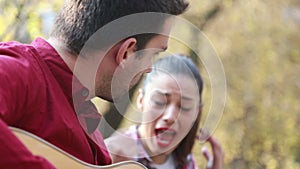 Brunette woman singing while man playing guitar