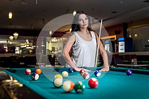 Brunette woman standing behind billiard table