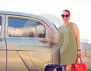 Brunette woman standing near retro car