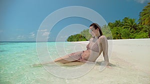 Brunette woman in sunglasses sunbathes on ocean beach edge
