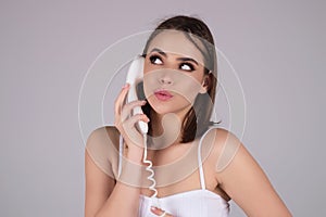 Brunette woman talking on retro line phone. Portrait of woman holding vintage telephone. Pin up girl with phone handset