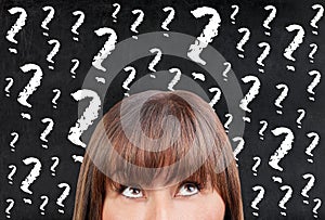 Brunette Woman thinking against blackboard chalkboard question marks