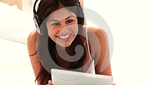 Brunette woman using a tablet pc while listening to music