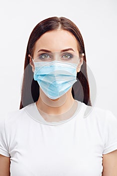 Brunette woman wearing disposable mask looks with an angry eyes