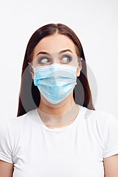 Brunette woman wearing disposable mask looks left with wide open eyes