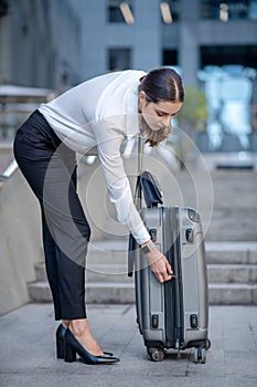 Brunette woman in white shirt zipping her suitcase