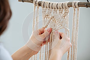 Craftswoman weving ropes, creating a macrame banner. from behind photo
