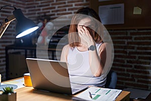 Brunette woman working at the office at night tired rubbing nose and eyes feeling fatigue and headache