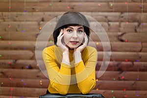 A brunette woman in a yellow jacket with a collar is leaning  high