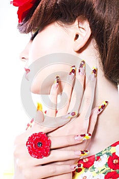 Brunette woman in yellow and red dress with poppy flower in her hair, poppy ring and creative nails, closed eyes