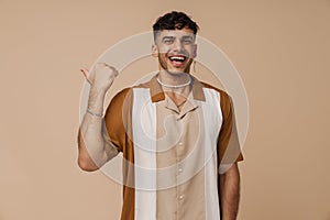 Brunette young man laughing and pointing finger aside