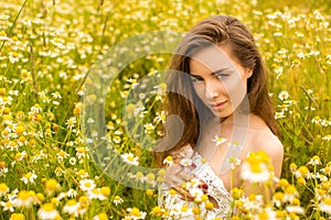 brunette young woman in chamomile field