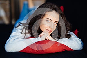 Brunette young woman hugging a pillow sitiing on sofa