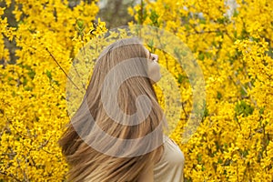 Brunette young woman with natural makeup and healthy long brown hair in blossom park outdoors. Natural female beauty portrait