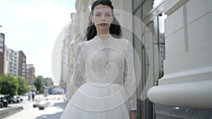 A brunnet is standing in a wedding dress