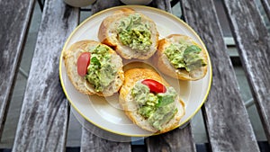 Bruschetta with avocado, basil and cherry tomato served on rustic table