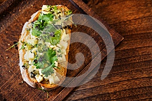 bruschetta with cheese and greens on a wooden cutting board for photos